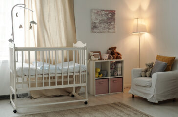 Interior of large contemporary room of baby with cradle and furniture