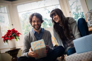 USA,A couple on a sofa, exchanging wrapped presents.